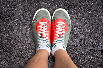 Legs with sports shoes colored with a red heart, asphalt background