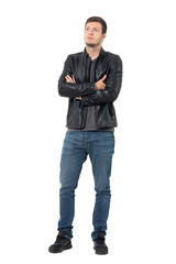 Young casual man in jeans and leather jacket with crossed arms looking up. Full body length portrait isolated over white background.