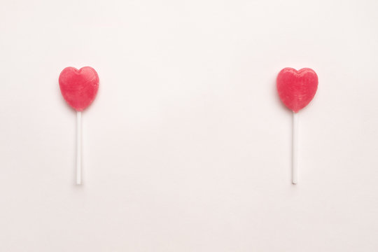 two Pink Valentine's day heart shape lollipop candy on empty white paper background. Love Concept. Knolling top view. Minimalism colorful hipster style.