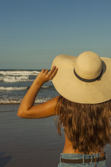 Young woman from behind, wearing beach summer hat