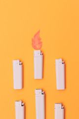 white lighters with painted flames on orange background. fashion flat lay set.