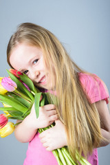 Obraz na płótnie Canvas Smiling blond girl with a bouquet of tulips.