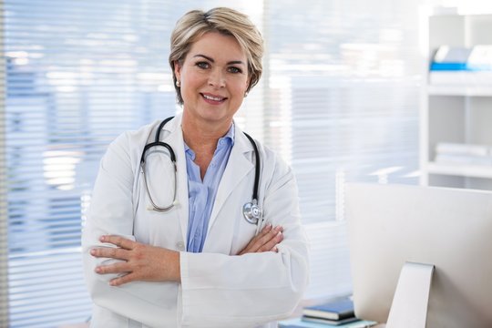 Portrait of a smiling female doctor standing with arms crossed