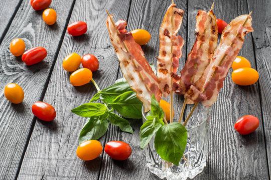 Grilled bacon on skewers in a glass and cherry tomatoes