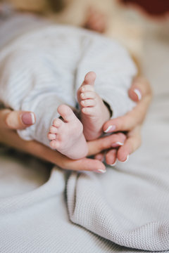 A newborn baby in his bed at home. Close up of feet in mother's hands