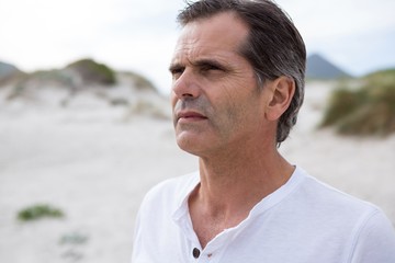 Thoughtful man standing on beach