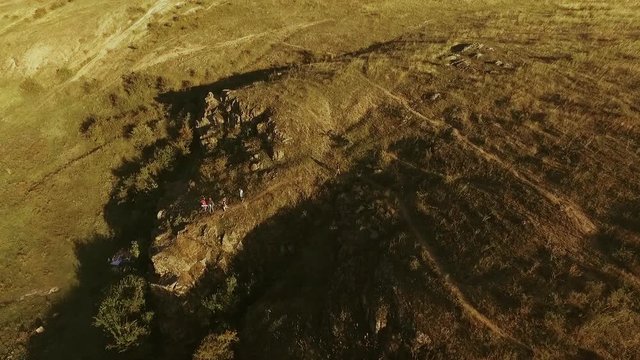 Panoramic view from drone in slowmotion with tilt on hilled country with group of tourists near camping