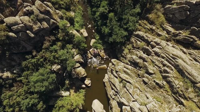 Panoramic view of in riverbed with rocky riversides and big boulders with swimming people. Panoramic view from drone in slowmotion