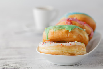 Stack of iced donuts with coffee cup on table