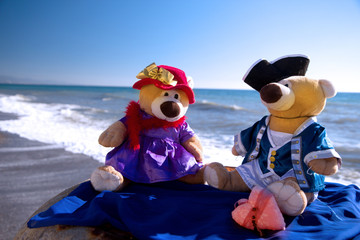 Obraz na płótnie Canvas Teddy bears's love date at the seashore at Saint Valentine's day. Blurred pebble background. Copy space for text.