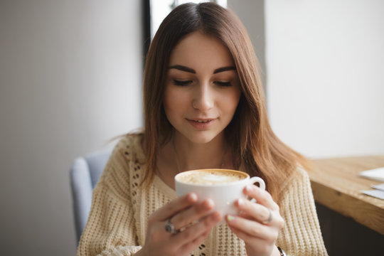 Lovely woman blowing on cup of coffee in a cafe