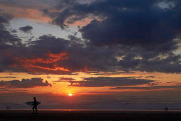 Fototapeta premium Surfer on the ocean beach at sunset or sunrise