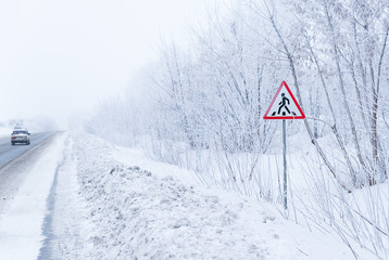 A road sign stands on the snowy roadside