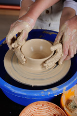 adult hand fed baby's hands to work with a potter's wheel