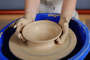 children's hands against the background of a potter's wheel close-up. a bowl of clay