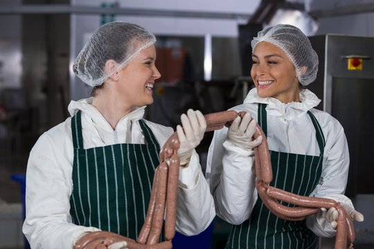 Female butchers processing sausages