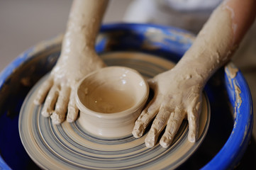 children's hands against the background of a potter's wheel close-up. a bowl of clay