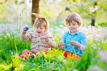 Two little boy friends in Easter bunny ears during egg hunt