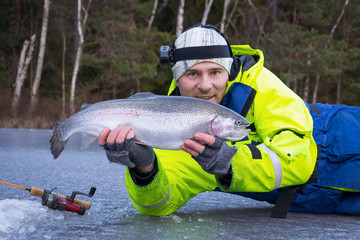Happy angler with huge rainbow trout icefishing trophy