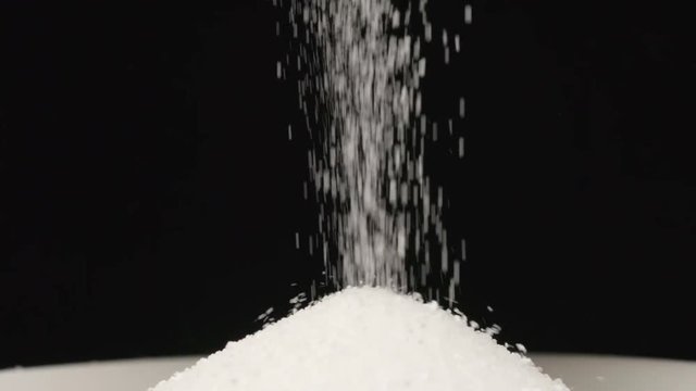 SLOW MOTION: Macro shot of falling of salt on a heap in a dish