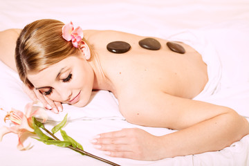 Obraz na płótnie Canvas Attractive woman laying on stone massage spa bed white background, portrait closeup