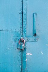 Hanging metal lock on emerald paint color metallic door. Closed private object vintage style