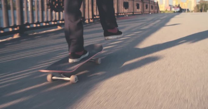 Closeup of legs of man riding skateboard on urban street with briefcase