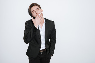 Fototapeta premium Attractive businessman posing at studio while holding cigarette.