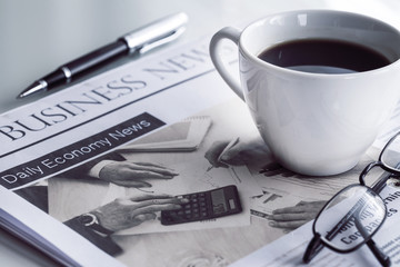 Newspaper with eyeglasses on white table