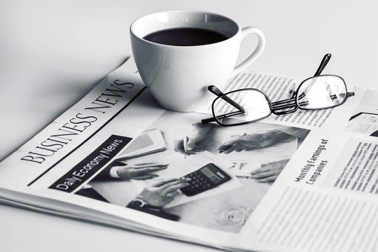 Newspaper with eyeglasses on white table