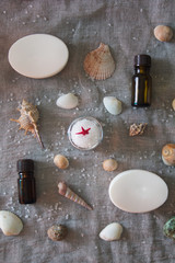 Fototapeta na wymiar Seashells, soap, aroma oil and a jar of sea salt on a grey cloth background. Spa concept.