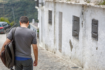 A tourist descends a street in a small village