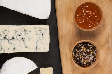 Sliced cheese, bowls of jam and spices on chopping board