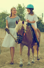 Woman leading pony with little girl.