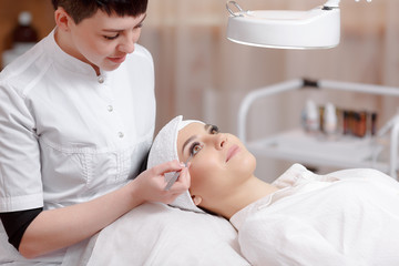 Obraz na płótnie Canvas Stylist making eyelash extension for women in beauty salon.