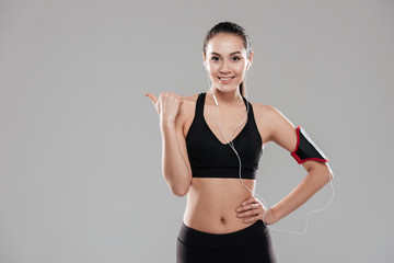 Fototapeta na wymiar Happy attractive young fitness lady posing and pointing