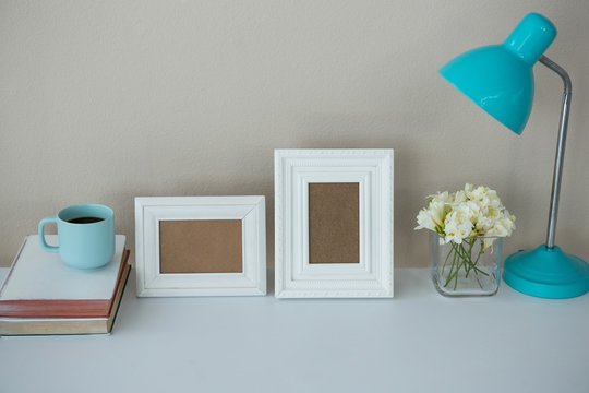 Picture frames, coffee cup with table lamp and flower vase