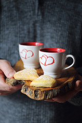 Valentine's Day: two cups of coffee in the men's hands and heart
