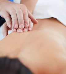 Macro close up of hands massaging female back.