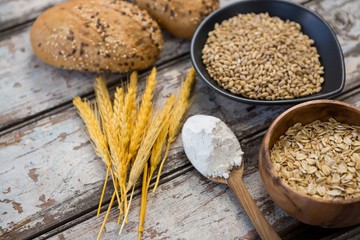 Wheat grains with bread buns, oats and spoon full of flour