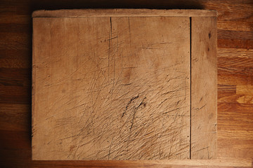 Side of a very old and heavily used chopping board with deep cuts on a beautiful brown wooden table
