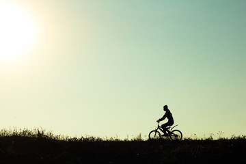 Obraz na płótnie Canvas Silhouette of a female cyclist riding Movement on the background