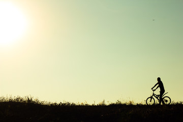 Obraz premium Silhouette of a female cyclist riding Movement on the background
