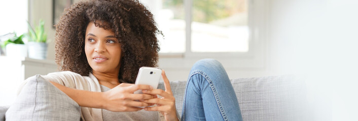 Woman relaxing in sofa and using smartphone