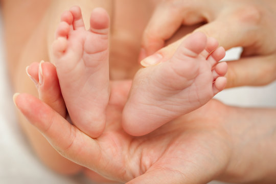 Small feet of baby new born that hold in her moms hand.