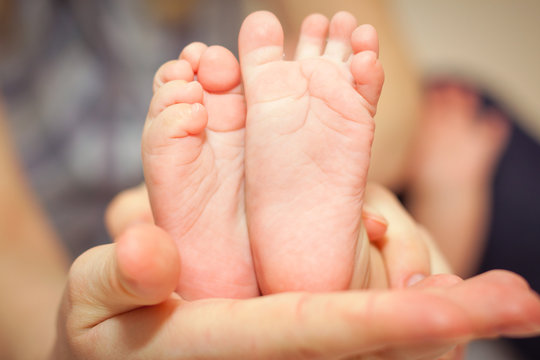 Small feet of baby new born that hold in her moms hand.