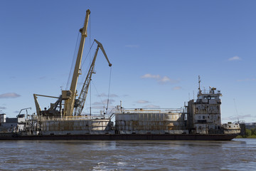 Fototapeta premium River cranes and oil tanker under load. Indigirka River. Yakutia. Russia.