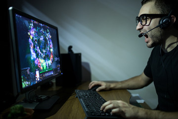 young gamer in headphones and glasses using computer for playing game at home in the night © F8  \ Suport Ukraine