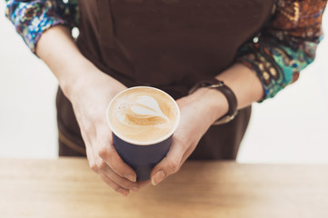 Barista holding coffee in a coffee shop. Professional coffee making, service and catering concept