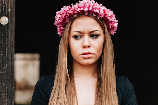 Portrait of a blonde girl with a pink wreath of flowers on her h